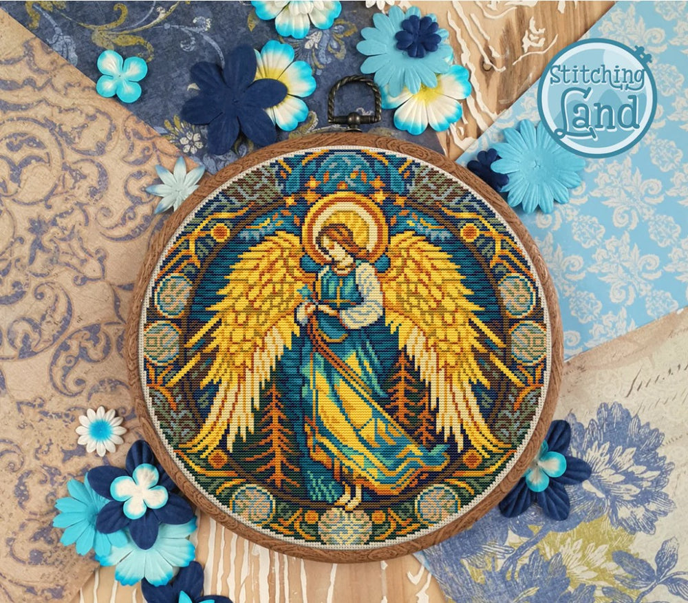 Stamped cross stitch design of an angel design surrounded by decorative flowers on a textured fabric background.