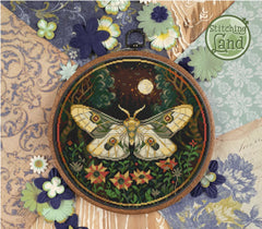 Stamped cross stitch design of a moth design on a textured fabric background with flowers.