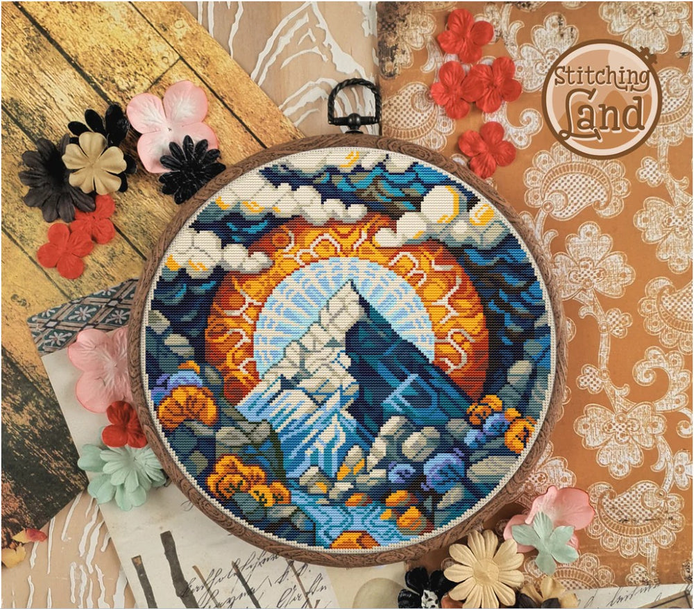 Stamped cross stitch design of a mountain scene, surrounded by decorative flowers