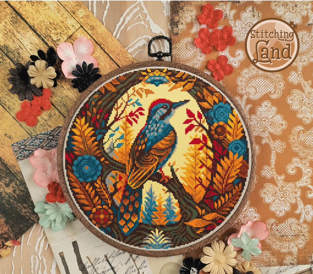 Stamped cross stitch design of a colorful bird design on a wooden surface with flowers.