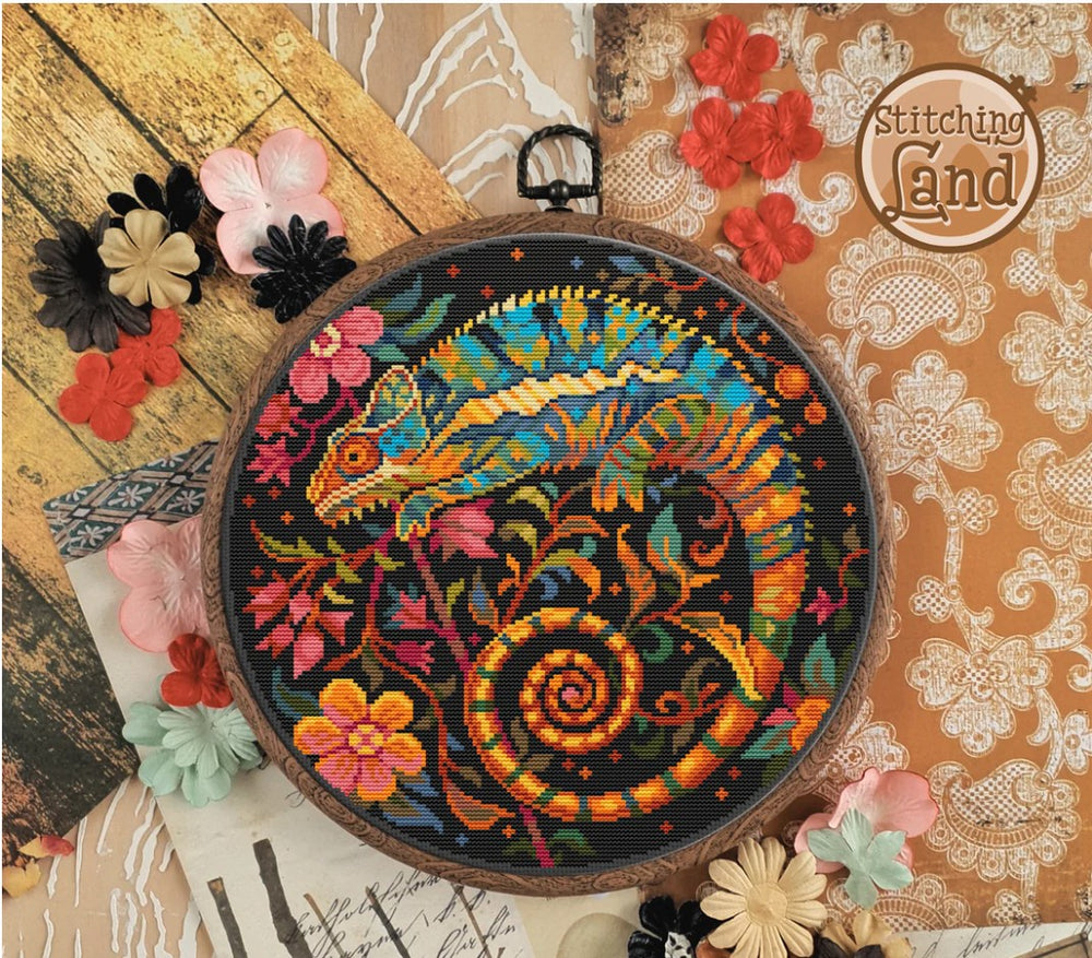 Stamped cross stitch design of an Embroidery hoop with colorful chameleon design on a decorative background with flowers.
