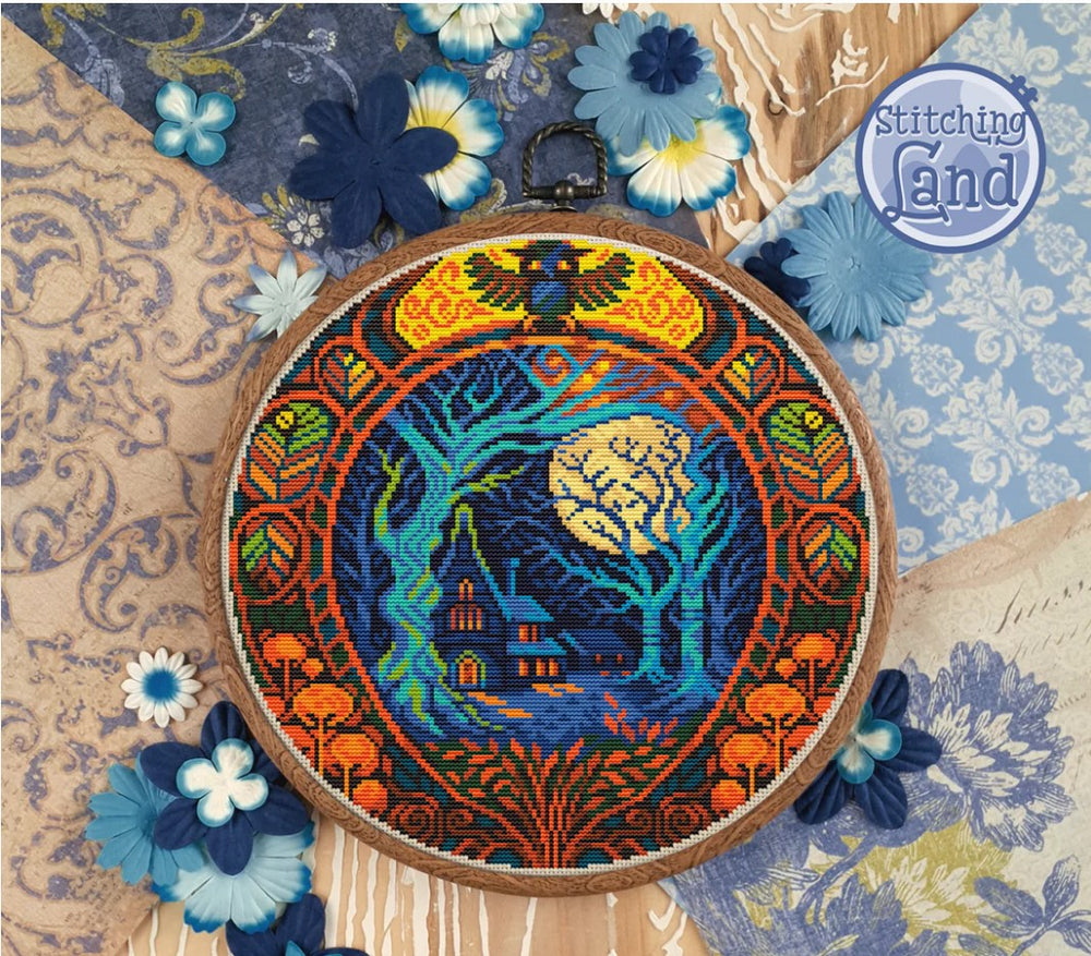 Stamped cross stitch design of a house and forest in front of a full moon