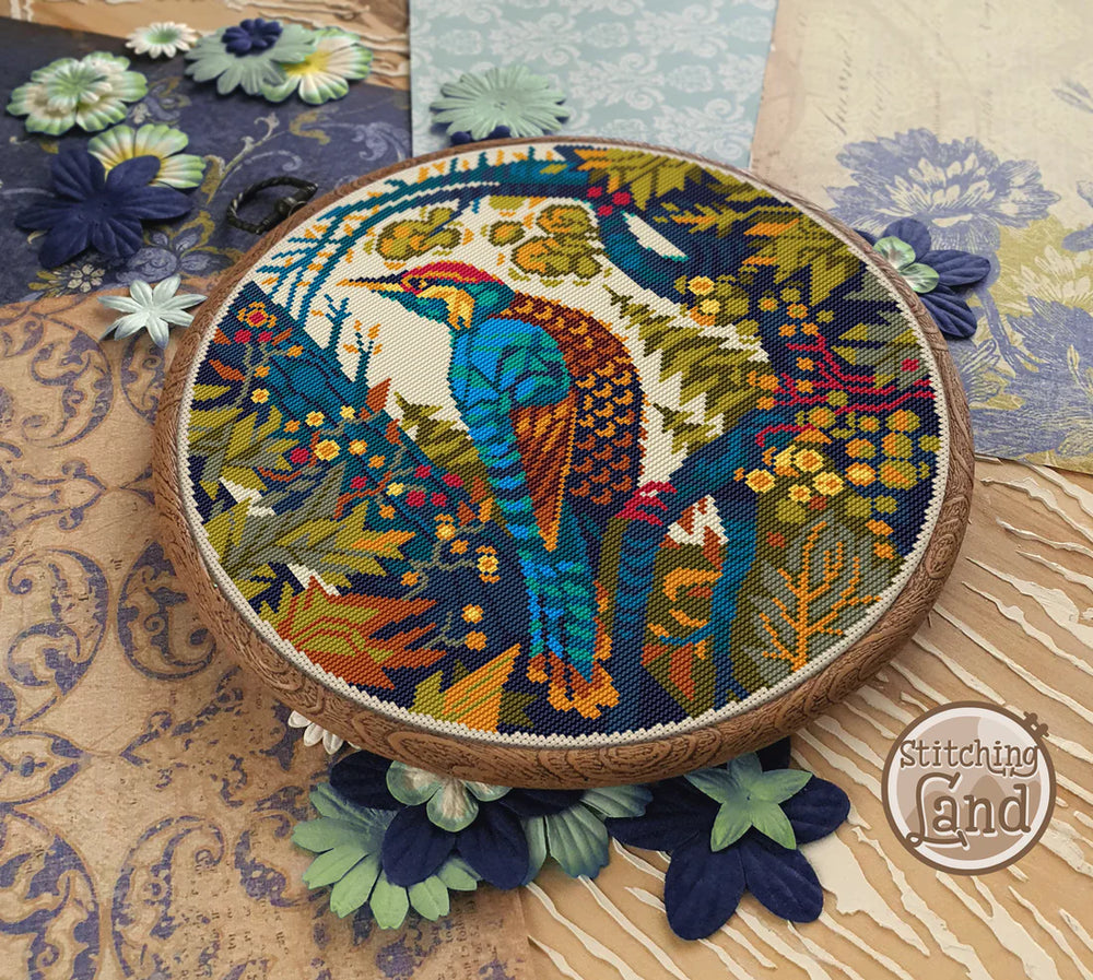 Embroidery hoop with a colorful peacock design on a floral background, featuring the brand 'Stitching Land'.