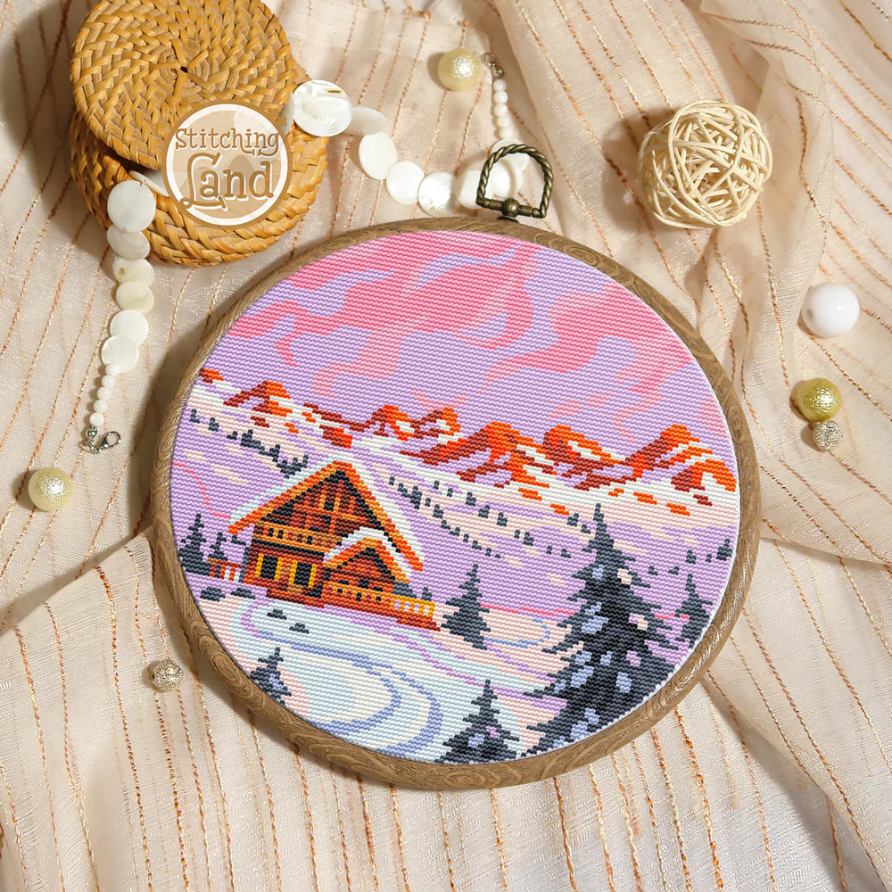 Stamped cross stitch mockup showing a Embroidery hoop with a winter landscape design on a textured surface with embroidery supplies.
