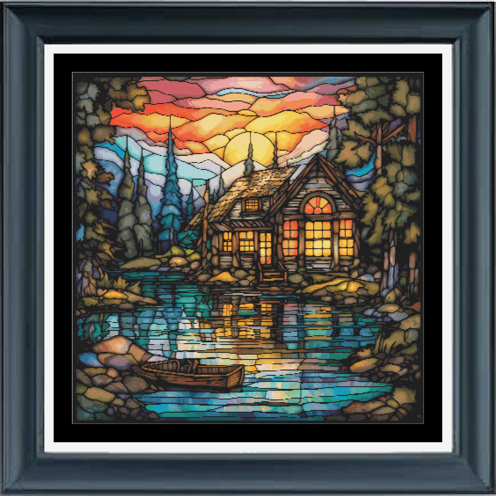 A stained glass Stamped cross stitch kit depicting a cabin on a lake with a boat, trees, and a sunset in the background.