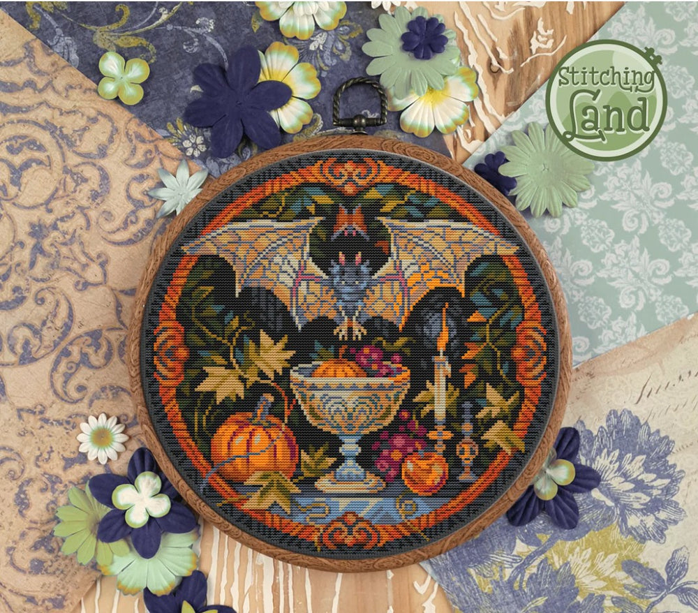 Decorative stamped cross-stitch kit with a bat, pumpkin, and floral elements on a textured fabric background.