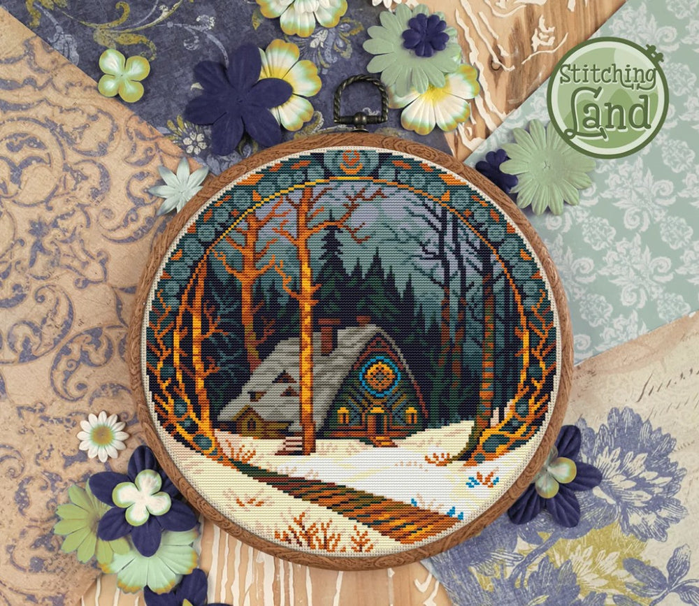 Stamped cross stitch design of a Embroidery hoop with a winter scene of a cabin in the woods, surrounded by decorative flowers and fabric.