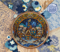 Mockup of a stamped cross stitch showing a of a village scene in an embroidery hoop with decorative flowers and 'Stitching Land' branding.