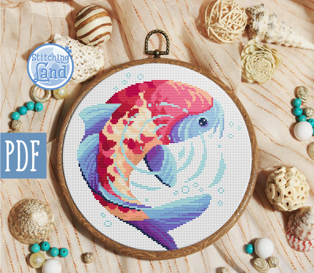 Stamped cross stitch mockup of a colorful fish design on a wooden hoop, surrounded by decorative items.
