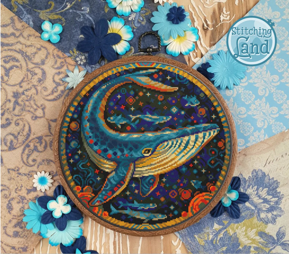Stamped cross stitch design of  a whale design surrounded by decorative flowers and 'Stitching Land' branding.