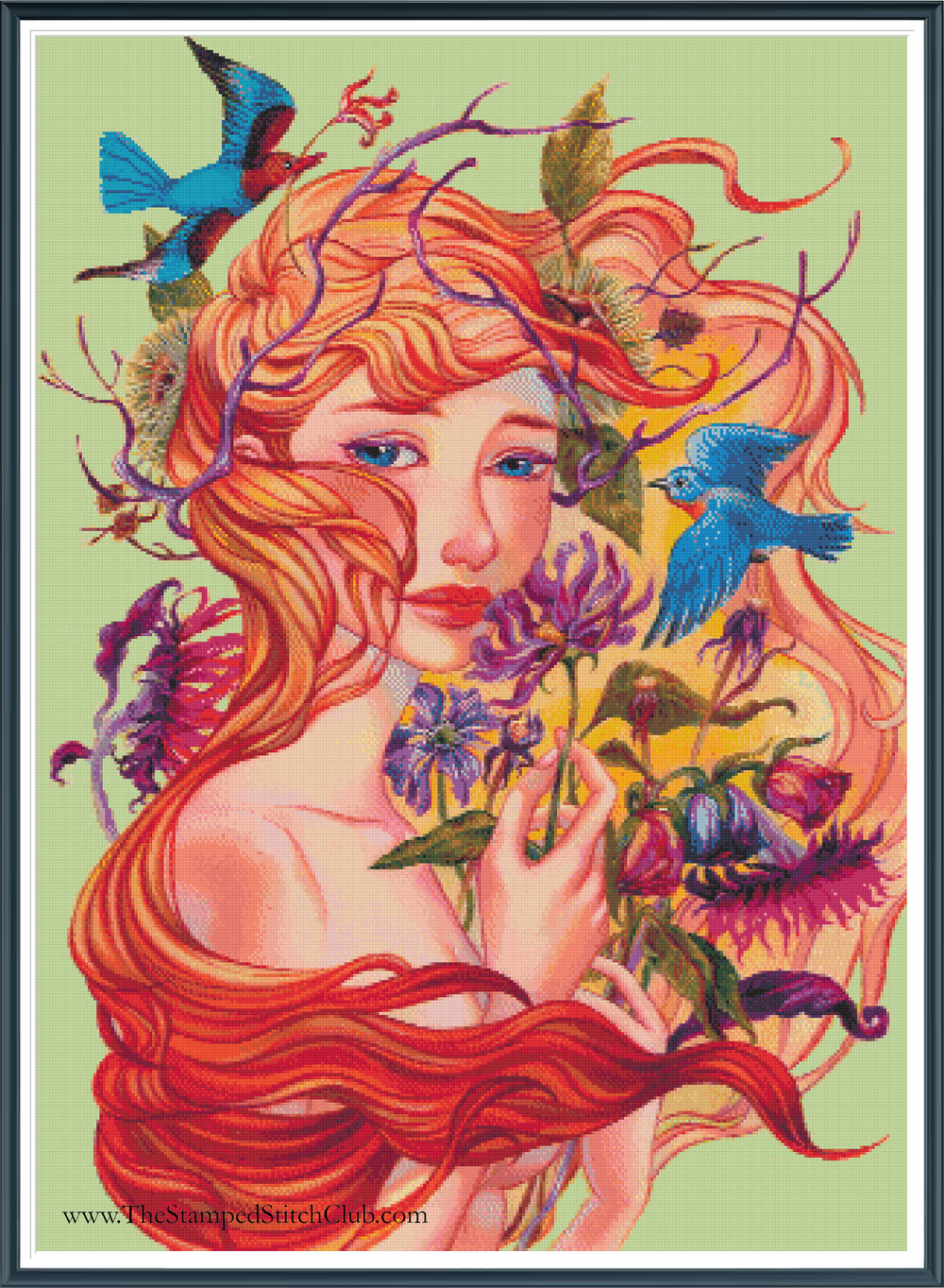 Framed cross stitch mock-up of Autumn by Maria Abignale, available from The Stamped Stitch Club. A beautiful fantasy portrait of a woman with flowing copper-red hair, surrounded by vibrant autumn flowers, purple foliage and vivid blue birds against a soft green background.