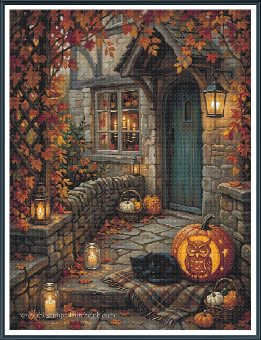 Framed cross stitch mock-up of Autumn at Owl Cottage by Ricco, available from The Stamped Stitch Club. A cosy stone cottage with a teal front door, glowing lanterns and rich autumn foliage. A black cat rests beside a carved owl pumpkin, surrounded by fallen leaves, smaller pumpkins and baskets on the cottage steps.
